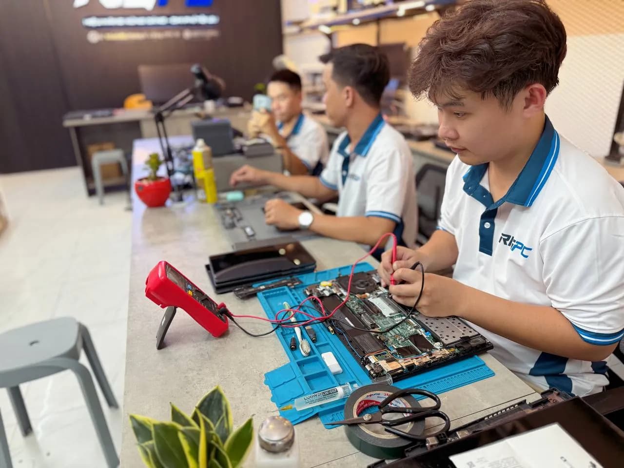 Kỹ thuật viên RIGPC đo mainboard laptop bằng đồng hồ vạn năng